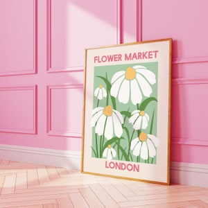 May include: A framed print with a green background and white daisies. The print says "FLOWER MARKET LONDON" in pink and white text.