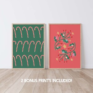 May include: Two framed Christmas prints. The print on the left features a green background with a repeating pattern of red and white candy canes. The print on the right features a red background with a stylized illustration of holly branches with red berries and gold stars.