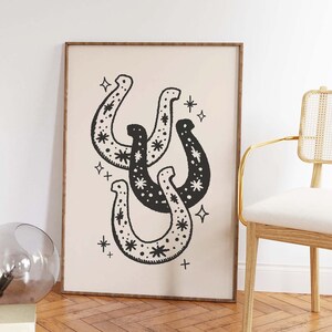 May include: Black and white illustration of four horseshoes with a star pattern. The horseshoes are overlapping and arranged in a cluster. The background is a light beige color.