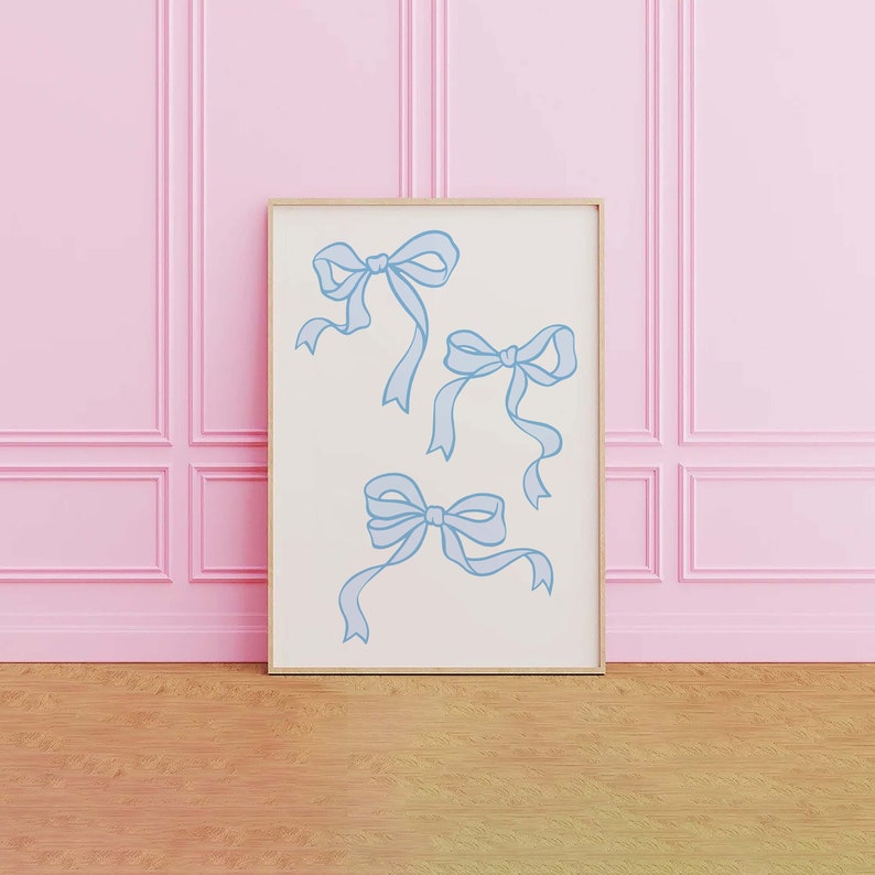 May include: A framed print with a white background and four blue bows drawn on it. The print is hanging on a pink wall.