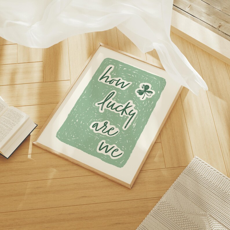 May include: A framed print with a green background and white text that reads "how lucky are we". A green shamrock is in the upper right corner of the print.