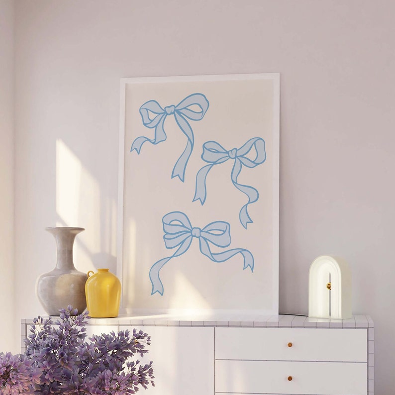 May include: A framed print with a white background and four blue ribbon bows. The bows are drawn in a simple, minimalist style.