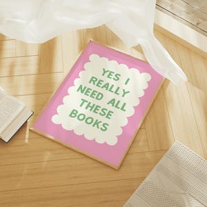 May include: A pink framed print with a white cloud shape containing the text "YES I REALLY NEED ALL THESE BOOKS" in green letters.