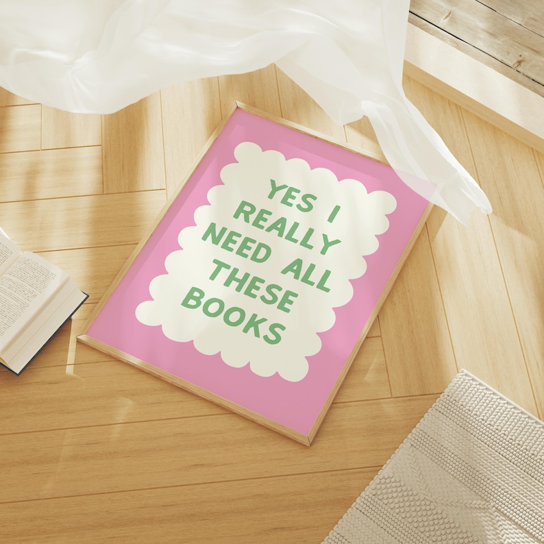May include: A pink framed print with a white cloud shape containing the text "YES I REALLY NEED ALL THESE BOOKS" in green letters.