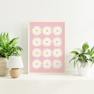 May include: A framed print with a pink background and a repeating pattern of white daisies with yellow centers.