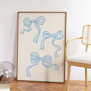 May include: A framed print with a white background and three blue bows. The bows are drawn in a simple, stylized way.