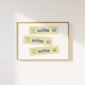 May include: Three yellow and blue labels with the text "SALTED BUTTER GRADE AA" and "NET WT. 4 OZ (113g)" on a white background inside a gold frame.