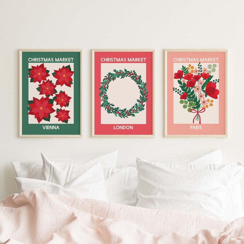 May include: Three Christmas market prints with a green, red, and pink background. The Vienna print features red poinsettia flowers. The London print features a green wreath with red berries. The Paris print features a bouquet of red flowers with green leaves.