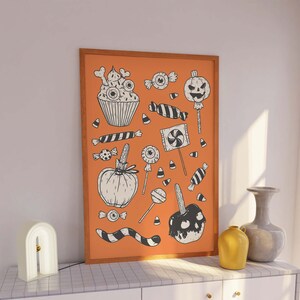 May include: A framed print with an orange background and black and white illustrations of Halloween treats, including cupcakes, candy corn, lollipops, and candy apples.