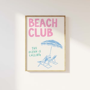 Pu&ograve; includere: Un poster bianco con un'illustrazione rosa e blu di sedie da spiaggia e un ombrello. Il testo "Beach Club" &egrave; in rosa e il testo "The ocean is calling" &egrave; in verde.