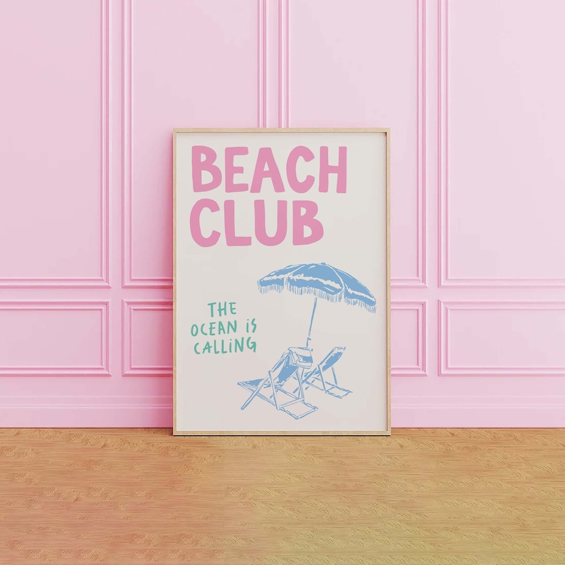 Pu&ograve; includere: Una stampa incorniciata con il testo "Beach Club" in lettere rosa e il testo "The ocean is calling" in lettere verdi. La stampa presenta un ombrellone da spiaggia blu e due sedie a sdraio blu.