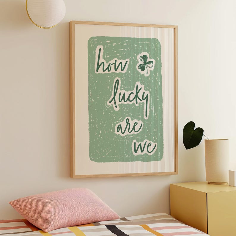 May include: A framed print with a green background and white text that reads "how lucky are we" with a four-leaf clover graphic.