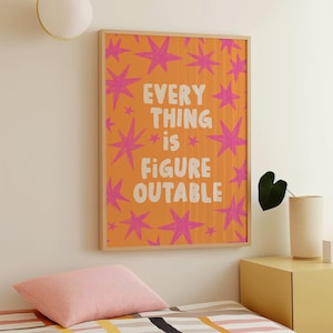 May include: A framed art print with an orange background and pink starburst designs. The print features the words "EVERY THING is FIGURE OUTABLE" in white lettering. The frame is a light wood color.