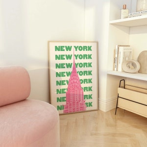 Pu&ograve; includere: Una stampa incorniciata con un'illustrazione rosa del Chrysler Building a New York City. Il testo "NEW YORK" &egrave; ripetuto in lettere verdi lungo il lato della stampa.