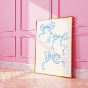 May include: A framed print with a white background and three blue ribbon bows. The bows are drawn in a simple, minimalist style.