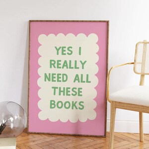 May include: A pink framed poster with a white scalloped border and green text that reads "YES I REALLY NEED ALL THESE BOOKS".