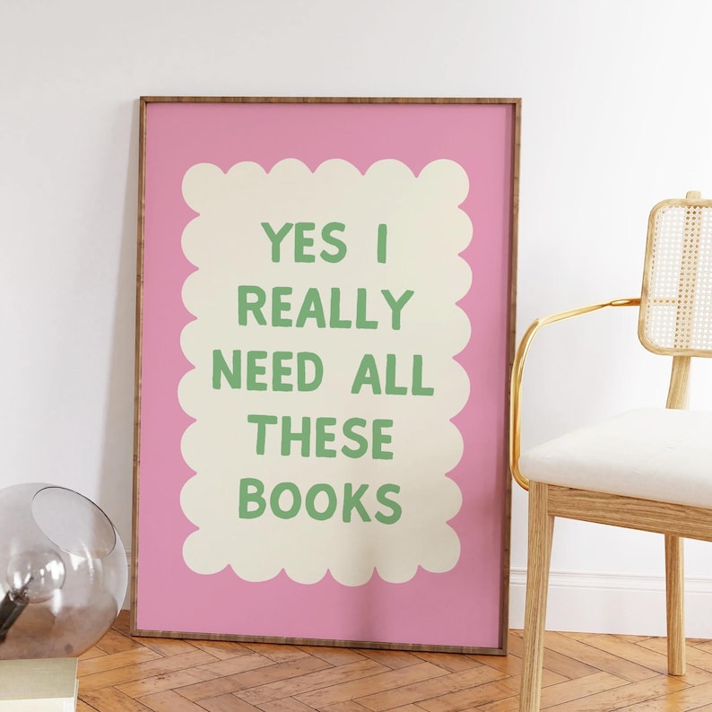 May include: A pink framed poster with a white scalloped border and green text that reads "YES I REALLY NEED ALL THESE BOOKS".