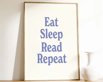 May include: A white framed print with the text "Eat Sleep Read Repeat" in a light purple color.