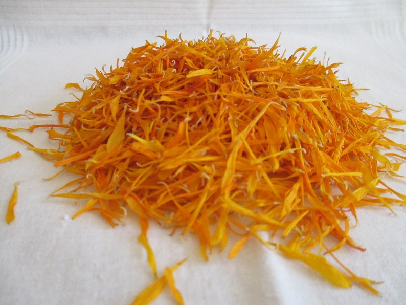 Pu&ograve; includere: Un mucchio di petali di calendula essiccati di colore arancione. I petali sono lunghi e sottili e sono disposti in un mucchio sciolto.