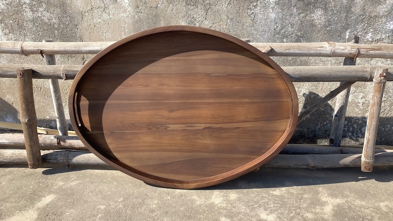 Puede incluir: Bandeja ovalada de madera para servir con asas integradas. La bandeja es de madera marr&oacute;n oscuro y tiene un acabado liso y pulido. La bandeja mide aproximadamente 61 cm de largo y 41 cm de ancho, ideal para servir alimentos o exhibir objetos decorativos.