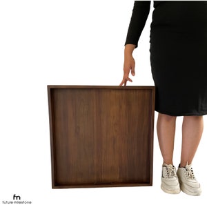 May include: A large, rectangular wooden serving tray with a dark brown finish. The tray is made of solid wood and has a smooth surface.