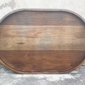 Puede incluir: Bandeja ovalada de madera con acabado de vetas naturales. La bandeja tiene un centro marr&oacute;n claro y bordes marr&oacute;n oscuro. La bandeja mide aproximadamente 46 cm de largo y 30 cm de ancho.
