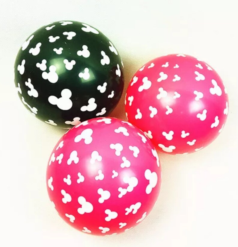 Puede incluir: Tres globos redondos con un patr&oacute;n de cabeza de Mickey Mouse blanca. Un globo es negro, uno es rosa y uno es de un tono rosa m&aacute;s brillante.
