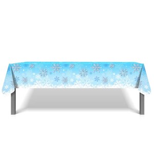 May include: A blue plastic tablecloth with a white snowflake pattern. The tablecloth is laid out on a table with silver legs.