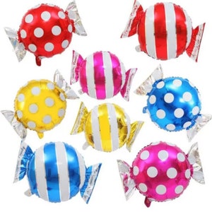 May include: Seven foil candy-shaped balloons in various colors and patterns. The balloons are red with white polka dots, red with white stripes, pink with white stripes, yellow with white polka dots, yellow with white stripes, blue with white stripes, and pink with white polka dots.