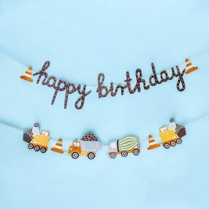 以下が含まれることがあります： 茶色の筆記体で「happy birthday」と書かれたお祝いの誕生日バナー。 バナーには、トラックや交通コーンなど、建設をテーマにした切り抜きが、水色の背景に配置されています。 建設をテーマにした誕生日パーティーに最適です。