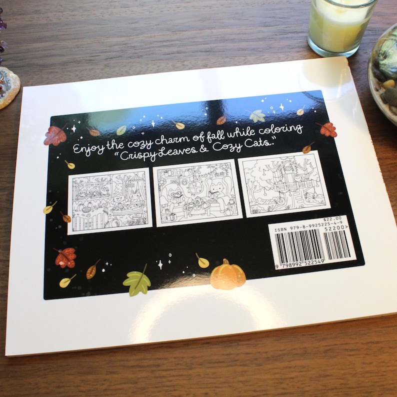 May include: A coloring book titled "Crispy Leaves & Cozy Cats" with a black cover featuring three black and white illustrations. The cover includes the text "Enjoy the cozy charm of fall while coloring." Autumn leaves and a pumpkin are also shown.