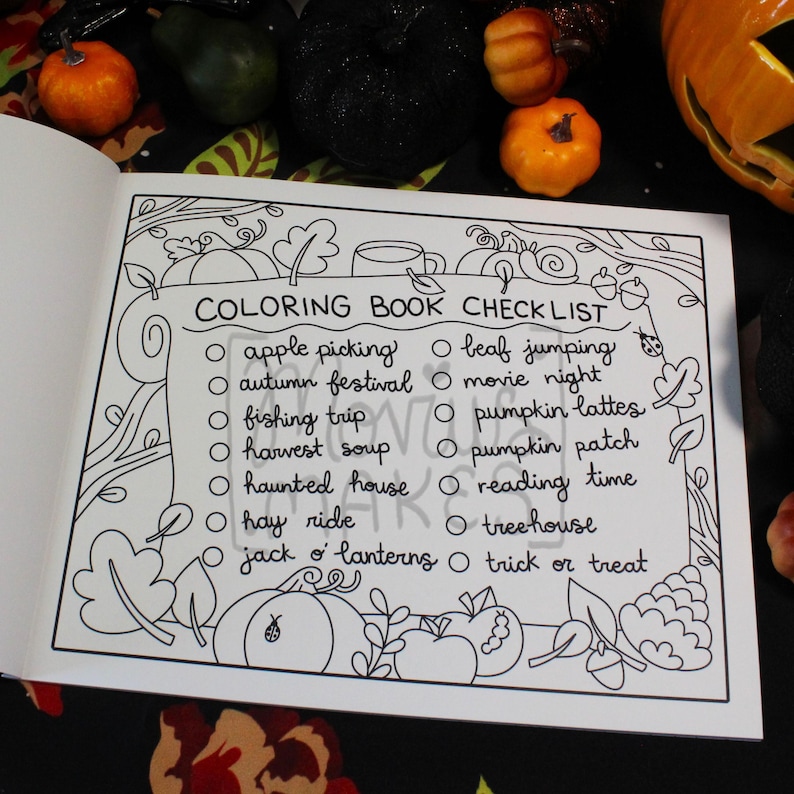 May include: Open coloring book page with a black and white outline of a checklist for fall activities. The checklist includes items like apple picking, haunted house, and trick or treat. Pumpkins and leaves decorate the border.