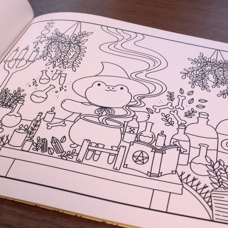 May include: A black and white line drawing of a frog wearing a witch's hat and stirring a cauldron. The frog is surrounded by various potion bottles, candles, and other magical items.