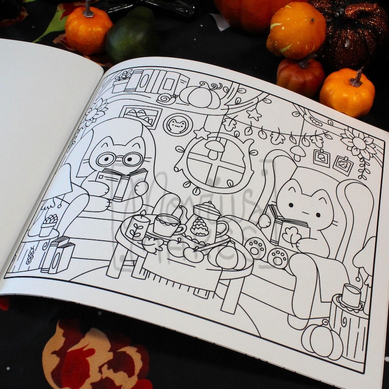 May include: A black and white coloring book page featuring a cozy autumn scene with cartoon cats. One cat wears glasses and reads a book, while another relaxes in a chair. Pumpkins and fall decor surround them, creating a warm, inviting atmosphere.