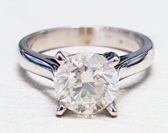 May include: A silver engagement ring with a large, round, clear diamond.