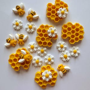 May include: A selection of yellow and black bee ornaments, white daisies, and yellow honeycomb designs. The bees feature white wings and black stripes. The daisies have white petals and yellow centres. The honeycomb designs have a hexagonal pattern.