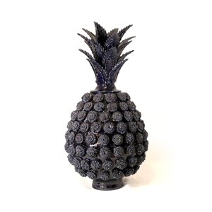 Op de afbeelding: Een donkerblauwe, ananasvormige decoratieve vaas. De vaas heeft een textuur met een patroon van kleine, ronde, bloemachtige vormen die het lichaam bedekken. De bovenkant heeft stekelige bladeren. De vaas is ongeveer 30 cm hoog.