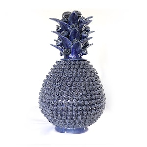 May include: A decorative blue ceramic pineapple sculpture. The pineapple features a textured body and detailed leafy crown. The sculpture is a unique home decor item, perfect for adding a touch of tropical flair to any space.