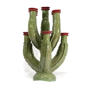 May include: A green ceramic cactus sculpture with multiple arms, each topped with a red rim. The cactus has a textured surface with small bumps, and it stands on a rounded base. The sculpture is a decorative item.