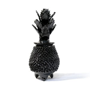 Puede incluir: Una taza de cerámica blanca con un asa negra y el texto "But First, Coffee" en negrita negra. La taza se encuentra sobre un fondo neutro, resaltando su diseño sencillo.