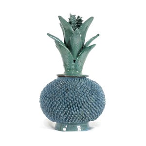 Puede incluir: Un jarrón decorativo de cerámica color turquesa con un cuerpo esférico texturizado y una parte superior en forma de piña. El jarrón tiene una textura detallada y espinosa en el cuerpo y una parte superior lisa y frondosa. La base es de color turquesa a juego.