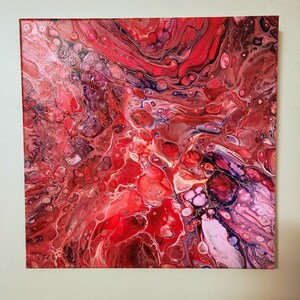 May include: A square canvas painting featuring an abstract fluid acrylic pour design. The composition displays a vibrant mix of deep red, bright crimson, soft pink, and dark purple tones, with swirling patterns and circular cell formations.