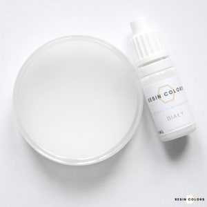 May include: A white resin pigment and a clear plastic container filled with white resin. The pigment bottle is labeled "Resin Colors" and "BIAŁY". The image is on a white background.