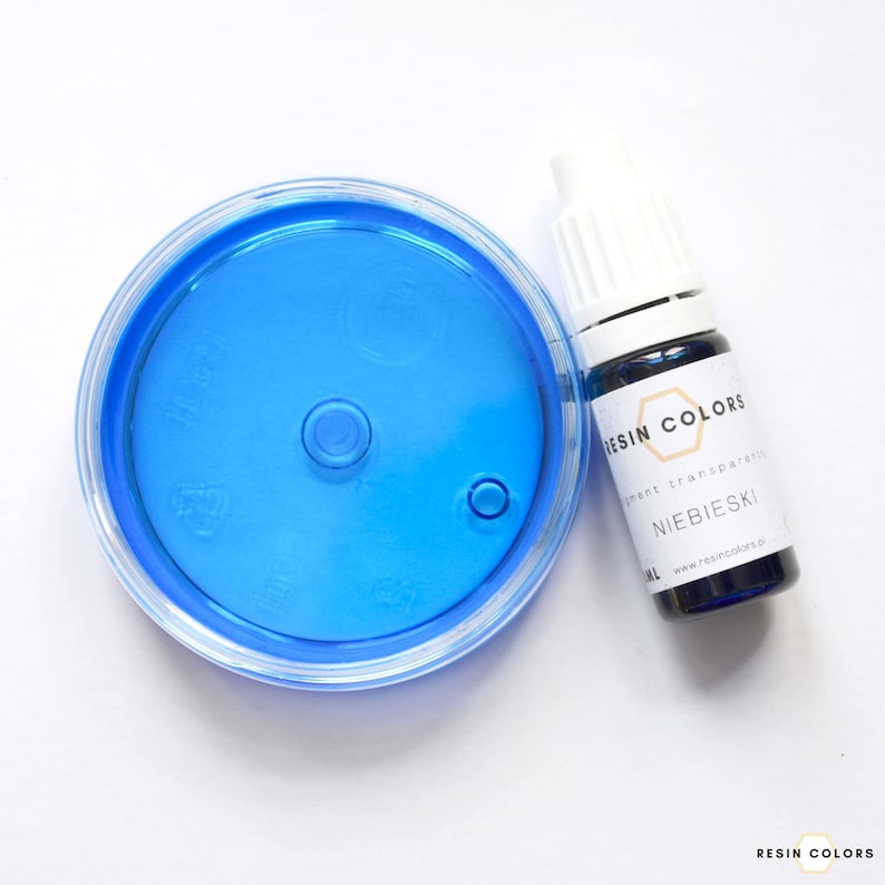 May include: A clear plastic container with a bright blue liquid and a small bottle of blue resin pigment. The bottle has a white cap and a label that reads "RESIN COLORS" and "NIEBIESKI".