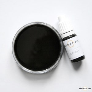 May include: A top-down view of a black resin dye and a bottle of resin dye. The dye is in a clear plastic container and the bottle has a white cap and a label that reads "RESIN COLORS" and "CZARNY".