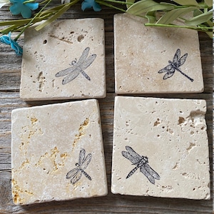 May include: Set of four square beige stone coasters with a black dragonfly design.