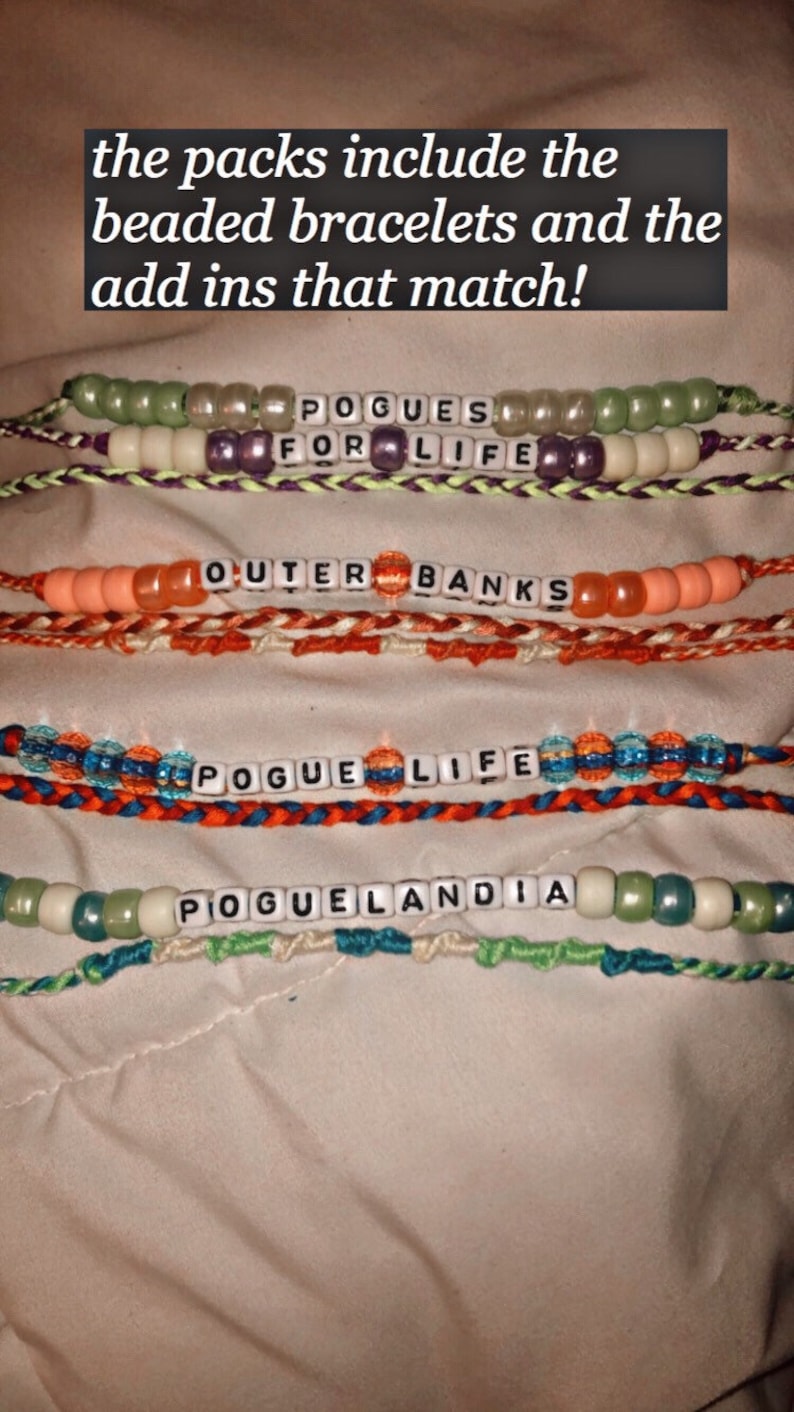 Puede incluir: Cuatro pulseras de cuentas con las palabras "Pogues for Life", "Outer Banks", "Pogue Life" y "Poguelandia" deletreadas en cuentas de letras blancas.