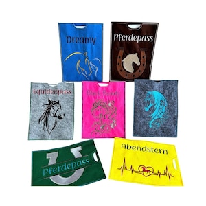Könnte beinhalten: Eine Sammlung von Filztaschen mit Pferdemotiven in verschiedenen Farben, darunter Blau, Braun, Rosa und Grau. Jede Tasche zeigt ein einzigartiges Pferdedesign und Text wie "Dreamy" und "Pferdepass". Die Taschen haben einen Griff oben.