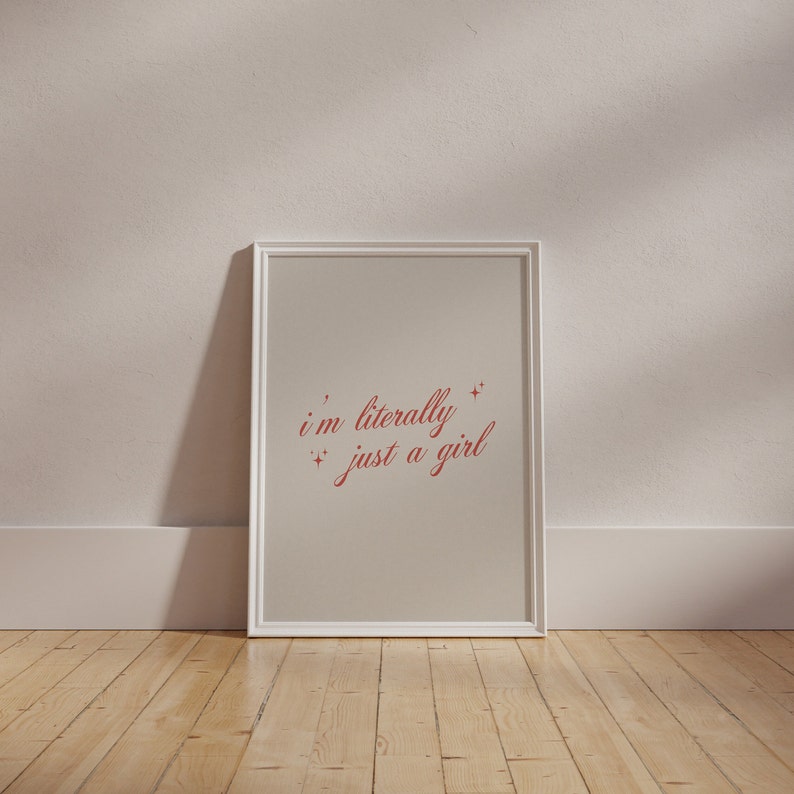 May include: A white framed print with a beige background and red text that reads "i'm literally just a girl" with small stars around the text.