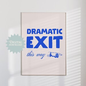 Può includere: Un download digitale stampabile di un cartello che dice "Uscita drammatica da questa parte" in testo blu con una grafica di mano che indica. Il cartello è su uno sfondo rosa.